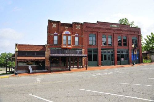 Historic buildings line a quiet street, featuring brick facades and colorful details under a clear blue sky.
