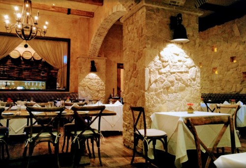 Cozy restaurant interior with stone walls, wooden tables, and soft lighting, creating an inviting atmosphere.