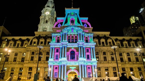 Colorful lights illuminate a historic building at night, showcasing vibrant patterns against its architectural details.