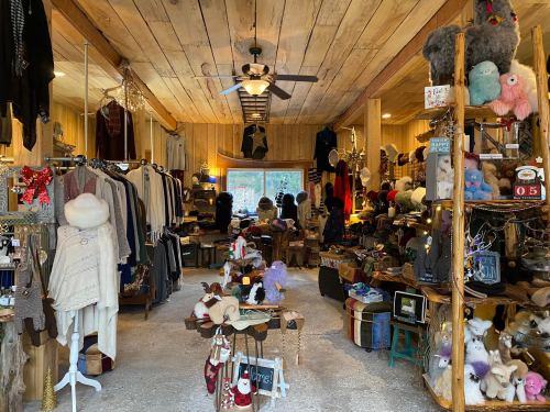 A cozy boutique filled with clothing, accessories, and handmade items, featuring wooden decor and a warm atmosphere.