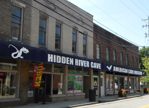 Exterior of the Hidden River Cave and American Cave Museum, featuring a blue awning and storefronts.