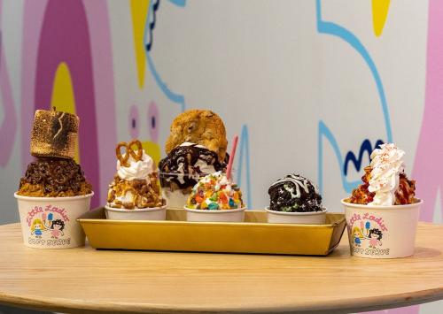 A colorful display of ice cream cups topped with various treats, set against a vibrant, playful background.