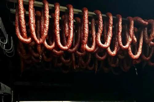 Hanging sausages drying in a dark, smoky environment.