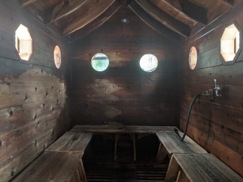 Interior of a wooden sauna with benches and circular windows, featuring a simple, rustic design.