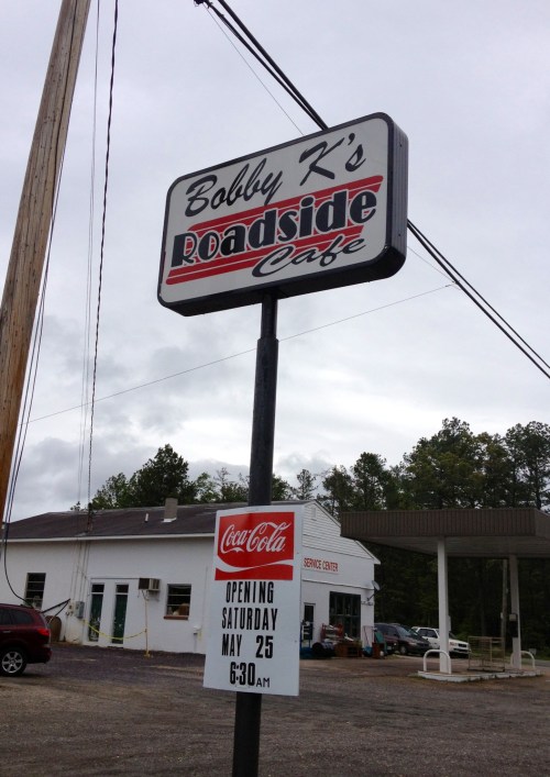 Sign for Bobby K's Roadside Cafe, announcing opening on May 25 at 6:30 AM, with a Coca-Cola logo.