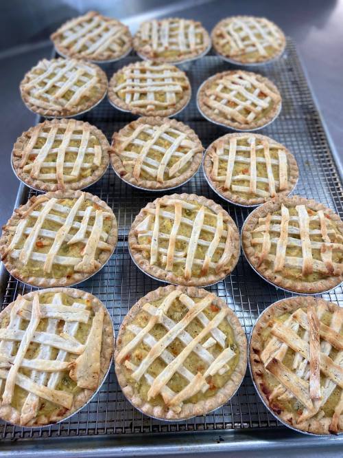 A tray of freshly baked mini pies with lattice crusts cooling on a wire rack.