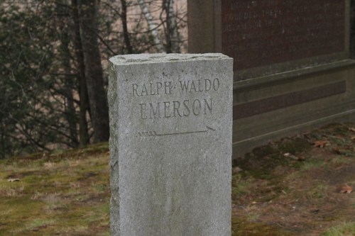 Gravestone of Ralph Waldo Emerson, featuring his name and an arrow pointing to the right, surrounded by nature.