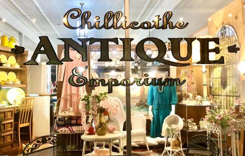 Sign for "Chillicothe Antique Emporium" displayed in a shop window, showcasing vintage decor and furniture.