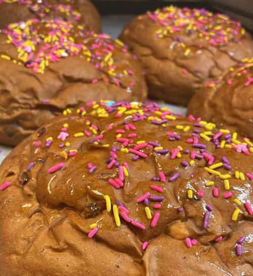 Close-up of freshly baked buns topped with colorful pink, yellow, and purple sprinkles.