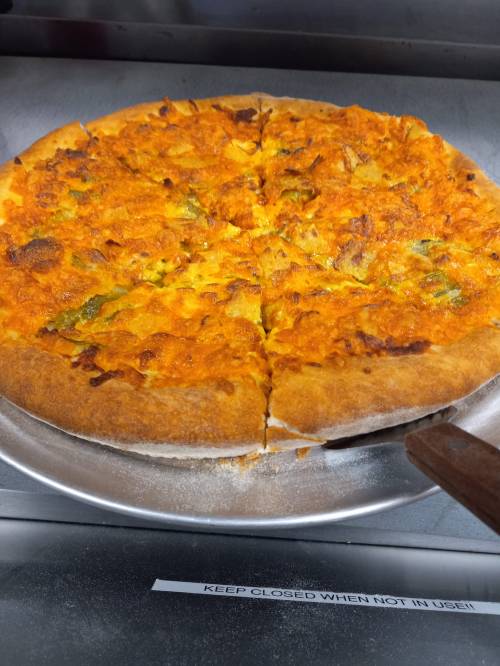 A freshly baked pizza with a golden crust, topped with orange cheese and green peppers, sliced into eight pieces.