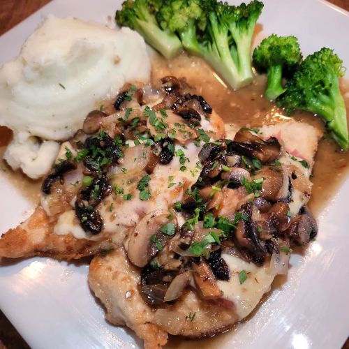 A plate featuring sautéed chicken topped with mushrooms, served with mashed potatoes and steamed broccoli.