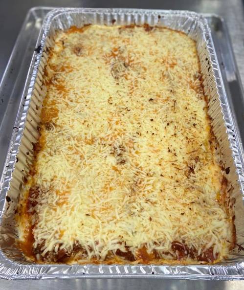 A large aluminum tray filled with baked lasagna topped with melted cheese.