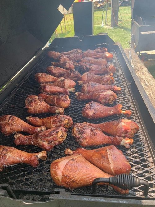 Grilled chicken drumsticks arranged on a barbecue grill, with a smoky appearance and a rich brown color.