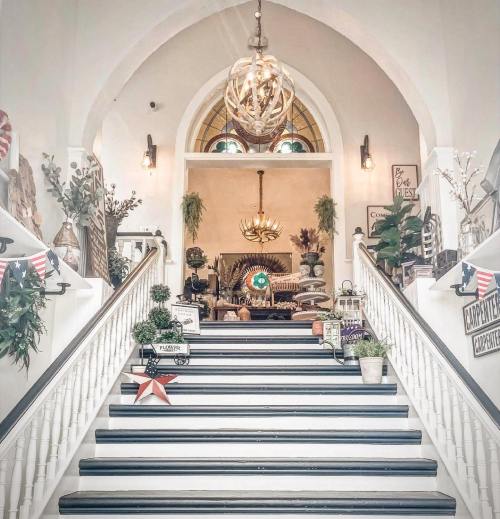 A beautifully decorated staircase leading to a bright, airy space with plants and vintage decor.