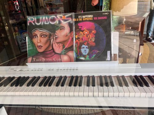 A display featuring two vinyl records and a white piano in a shop window.