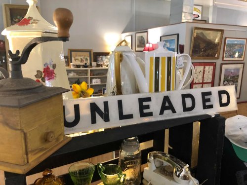 A vintage display featuring a sign that reads "UNLEADED," alongside various antique items and decor.