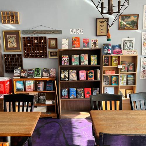 A cozy bookstore interior featuring shelves of new books, wooden tables, and colorful decor.