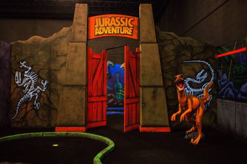 Entrance to a dinosaur-themed adventure area, featuring colorful murals and a T-Rex figure.