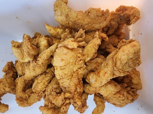 A close-up of a pile of crispy, golden-brown fried chicken pieces.