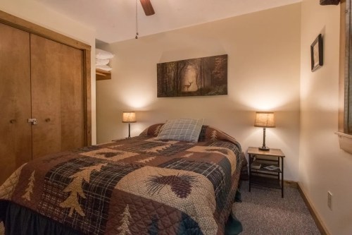 Cozy bedroom with a quilted bedspread, two lamps, and a nature-themed wall art featuring a deer.