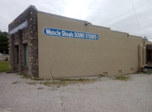 Exterior of Muscle Shoals Sound Studios, featuring a beige building with blue signage and decorative lights.