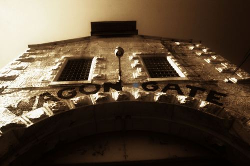 A close-up of the Wagon Gate, featuring textured stone walls and a vintage sepia tone.