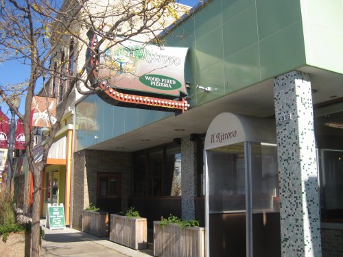 Exterior of Il Ritrovo, a wood-fired pizzeria, featuring a green facade and decorative signage.