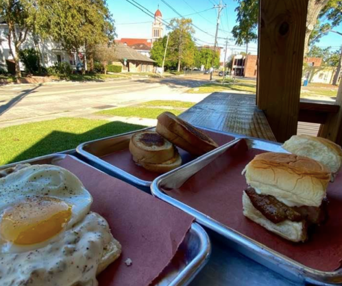 A view of a breakfast spread with eggs, toast, and a sandwich, set on a table with a street scene in the background.