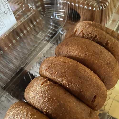 A close-up of several brown, round pastries arranged in a clear plastic container.