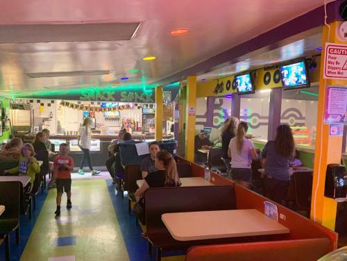 A colorful indoor space with people enjoying food and drinks, featuring arcade games and a lively atmosphere.
