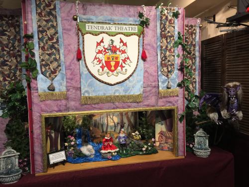 A colorful display for Tendrak Theatre featuring puppets, greenery, and decorative banners.