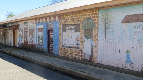 Colorful mural depicting a quaint street scene with shops and characters, enhancing the charm of the area.