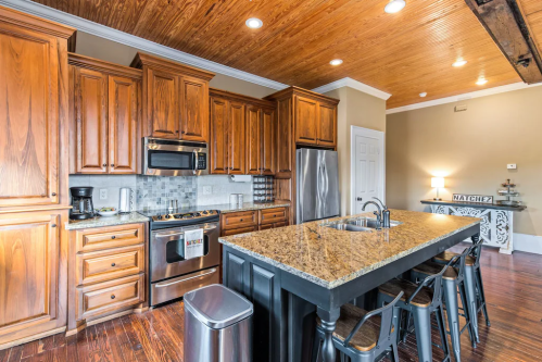Modern kitchen with wooden cabinets, granite island, stainless steel appliances, and a warm, inviting atmosphere.