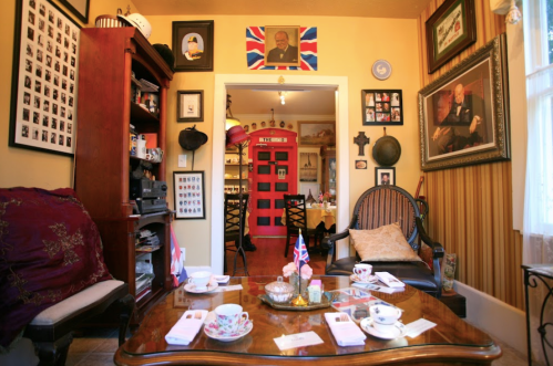 Cozy room with British decor, featuring a red phone booth, vintage furniture, and tea set on a table.