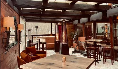 Cozy indoor seating area with wooden beams, warm lighting, and stylish furniture in a rustic setting.