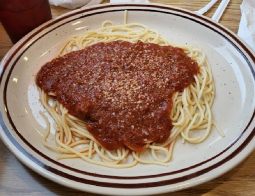 A plate of spaghetti topped with marinara sauce and sprinkled with grated cheese.