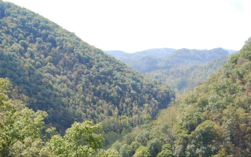 Lush green mountains and valleys under a bright sky, showcasing a serene natural landscape.