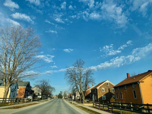 A quiet street lined with houses under a blue sky with scattered clouds and bare trees.