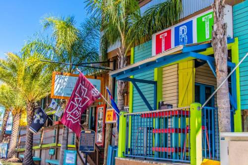 Colorful building with palm trees, featuring a sign that reads "TRT" and various flags hanging outside.