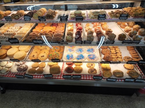 A display case filled with a variety of baked goods, including cookies, pastries, and donuts.