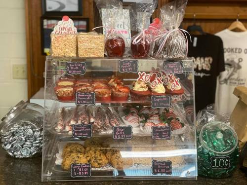 Display case filled with various baked goods, including cupcakes, cookies, and candies, all attractively arranged.