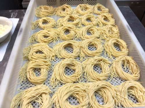 Freshly made pasta arranged in circular nests on a perforated tray, ready for drying.
