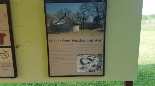 Signboard titled "Shelter from Weather and War" with images of historical buildings and a description of their significance.