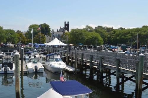 A marina with boats docked, a wooden pier, and a church in the background under a clear blue sky.