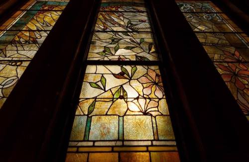 Stained glass window featuring intricate floral designs in vibrant colors and patterns.