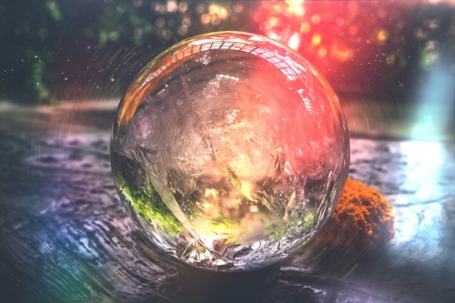 A crystal ball reflecting colorful light, set against a blurred, natural background.