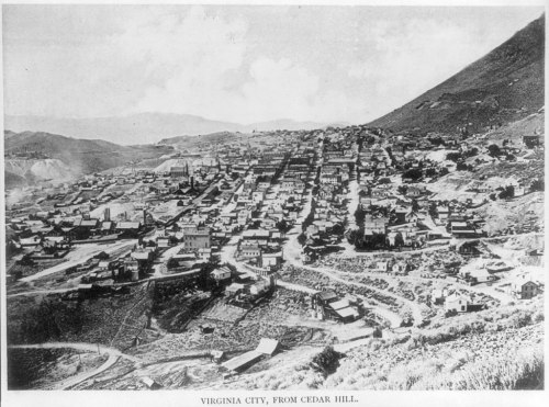 Black and white photo of Virginia City, showing a hillside view of the town with buildings and roads.