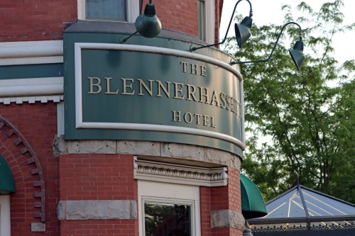 Sign for the Blennerhassett Hotel, featuring green and gold lettering on a brick building.