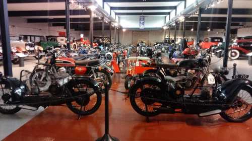 A vintage motorcycle museum filled with various classic motorcycles and cars, showcasing a rich automotive history.