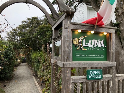 Sign for Luna Trattoria, featuring "Northern Italian Cuisine," with a pathway and decorative lights leading to the entrance.